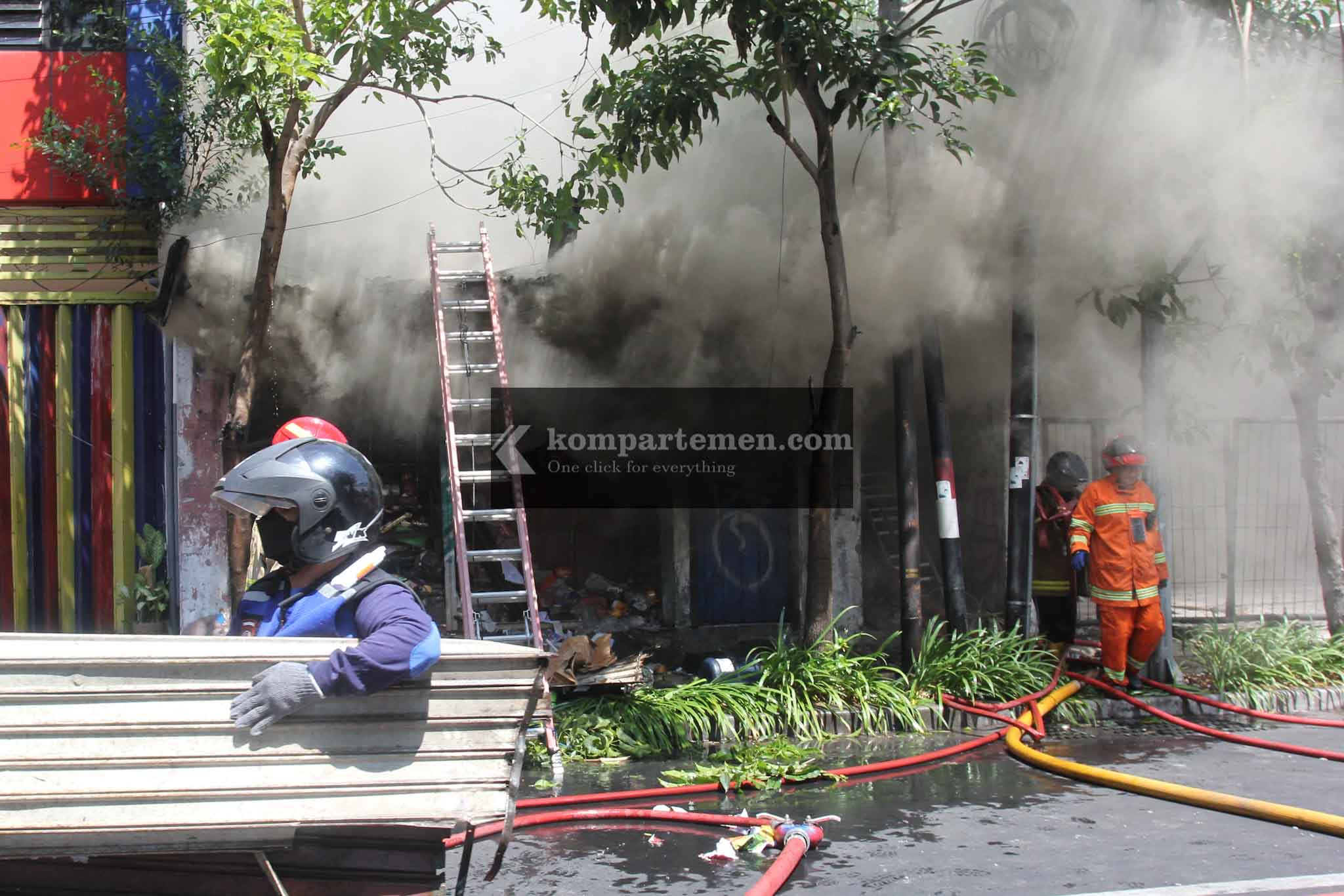 Petugas melakukan berusaha memindahkan material bangunan agar mempermudah pembasahan pada rumah yang terbakar di Jalan Kertajaya 138, Surabaya, Minggu (28/7/2024). Rumah yang ditempati oleh sepasang kakek dan nenek itu sudah kosong sejak Sabtu malam. Diduga kebakaran terjadi akibat arus pendek. DPKP Surabaya menerjunkan 14 armada pemadam dan dibantu 5 unit tanki dari Dinas Lingkungan Hidup (DLH) Surabaya. Foto: Kompartemen.com/Bima Sakti.